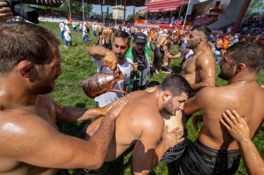 EDIRNE, TURKEY - JULY 14, 2018: Wrestlers have olive oil applied to their bodies prior to competition starting at the Kirkpinar Turkish Oil Wrestling Festival at Edirne in Turkey clipart