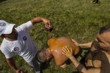 EDIRNE, TURKEY - JULY 14, 2018: Wrestlers have olive oil applied to their bodies prior to competition starting at the Kirkpinar Turkish Oil Wrestling Festival at Edirne in Turkey clipart