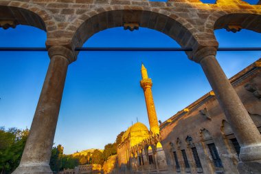 Sanliurfa 'daki Rizvaniye Camii, Balikligol (Balık Gölü). Tarihi İbrahim Havuzu ya da Kutsal Balık Havuzu. Günbatımında cami avlusundaki eski taş kemer arasında harika bir açı var.. 