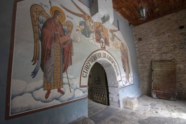BACHKOVO Manastırı, BULGARIA - 4 Haziran 2019: Manastırın dış avlusunda mumlarla dua edilir. Duvarlarda Bizans yapımı. Renkli çizimler ve İsa, Meryem, azizler ve meleklerin figürleri..