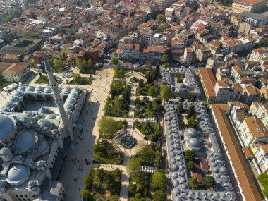 Fatih, camii ve parkı olan bir Türk şehir meydanını yüksek açılı görüyor. Meşhur bir camii ve parkı çevreleyen büyük bir meydana odaklanan hareketli bir Türk şehrinin hava görüntüsü.