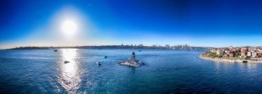 KIZ KULESI Maiden 'ın Güneşli Gökyüzü ile İstanbul Boğazı' nın Çarpıcı Hava Görüntüsü. İstanbul, Türkiye 'deki İstanbul Boğazı' nın panoramik hava manzarası, canlı şehir manzarası ve sakin suları gözler önüne seriyor.