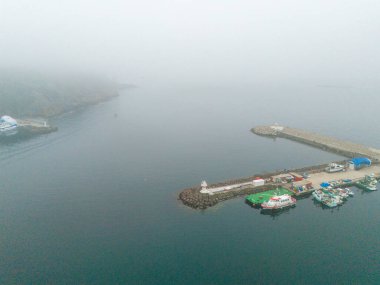 Tekneler ve denizaltılarla dolu sisli bir limanın havadan görüntüsü. Yüksek açılı, hafif bir sisle gizlenmiş bir liman sahnesinin tam görüntüsü. Poyrazkoy Beykoz İstanbul Türk Yavuz Sultan Selim Köprüsü