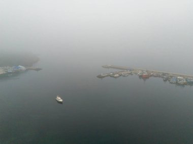 Tekneli Beykoz Misty Harbor Sahnesi. Sisli bir limanın yüksek açılı görüntüsü, çok sayıda rıhtımlı tekneyle sakin bir su kütlesi sergiliyor. Poyrazkoy Yavuz Sultan Selim Köprüsü İstanbul Türkiye Anadolu