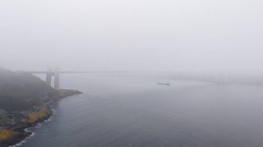 Beykoz Misty Coastal Bridge Sahnesi: Sisli bir denizin üzerindeki köprünün sakin bir görüntüsü. Kalın bir sisle örtülü bir su kütlesini kaplayan yüksek açılı, sakin bir köprü manzarası. Poyrazkoy İstanbul Türkiye 