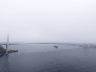 Köprüsü ve gemileri olan sisli bir limanın havadan görüntüsü. Sakin, hafif bulutlu, havadan çekilmiş bir liman görüntüsü. Poyrazkoy İstanbul Türkiye Beykoz Türk Yavuz Sultan Selim Köprüsü 