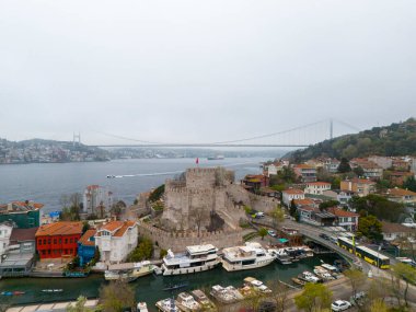 İstanbul 'un Tarihi Rumeli Kalesi ve Marina Havacılık Manzarası. Türkiye 'nin İstanbul kentindeki Anadolu Kalesi' nin yüksek açılı, tam görüntüsü. Tekneleri limana yanaşmış bir marina tarafından çekiliyor. Fatih Sultan Mehmet Köprüsü