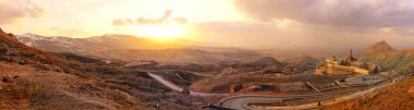 Gün doğumunda, dolambaçlı yol ve antik yerleşim yerleriyle dağlık bir manzara. Gün doğumunda nefes kesen panoramik engebeli bir dağ sırası. Ishak Paşa Sarayı Panoramik Doubeyazit Tarım Doğu Türkiye