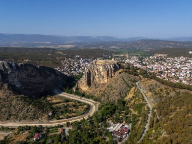 Türkiye 'nin Sinop kentindeki yüksek uçurumlarda Boyabat Kalesi' nin havadan panoramik manzarası vardı. Tarihi kale, ormanlık tepeler, dolambaçlı yollar ve Karadeniz 'in aşağısındaki modern şehirlerle çevrilidir.