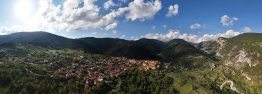 Bursa köyünün panoramik hava manzarası Türkiye 'nin yeşil dağlarına kurulmuştu. Geleneksel evleri, ormanlık tepeleri ve mavi gökyüzünde dramatik bulutları olan pitoresk bir kırsal alan.