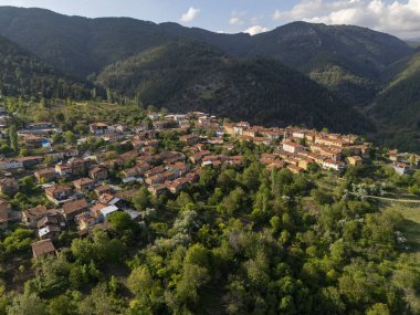 Bursa, Türkiye 'deki Gelemi köyünün insansız hava aracı görüntüsü. Ormanlık tepelerle çevrili kırmızı çatılı evleri ve bulutlu mavi gökyüzünün altında dramatik dağ manzarası olan pitoresk bir kırsal bölge.. 