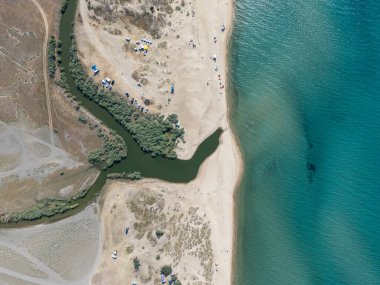 Nehrin denizle buluştuğu sakin bir sahilin yukarıdan aşağı manzarası. Çadırlar, kampçılar ve el değmemiş doğa plaj aşıkları ve açık hava meraklıları için mükemmel bir yaz kaçışı olur..