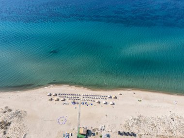 Türkiye 'nin Saros Körfezi' ndeki turkuaz deniz boyunca şemsiyeli ve güneşli kumsal manzarası. Yaz tatili, dinlenme, güneşlenme ve deniz kenarı tatili için mükemmel bir yer..