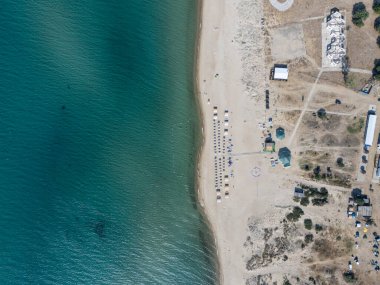 Türkiye 'nin Edirne kentindeki Saros Körfezi' nin berrak turkuaz suları boyunca güneşli şezlongları ve şemsiyeleri olan sakin kumlu bir sahil manzarası. Yaz tatili ve kıyı tatili için mükemmel..