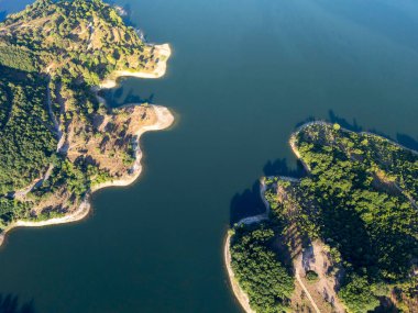 Merli Barajı 'nın tepeden tırnağa havadan görünüşü kavisli kıyı şeritlerinin ve yeşil ormanın sakin mavi sularla buluşmasının doğa, göl ve çevresel görüntüler için mükemmel doğal bir örneğini ortaya koyuyor..