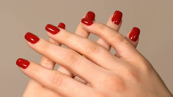 Womens hands are crossed. Fingers with red manicure are crossed in the frame. High quality photo