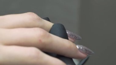 Manikürcü onun tırnaklarını gümüş jöle cilasıyla boyuyor. Yüksek kalite 4k görüntü