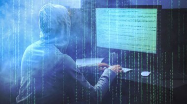 Erkek hacker Green Matrix koduna karşı bir bilgisayar üzerinde çalışıyor ve arka planda duman var. Bilgisayar matrisi kodlu bir bilgisayar korsanı. Kodlama, Tehlike, zararlı yazılım