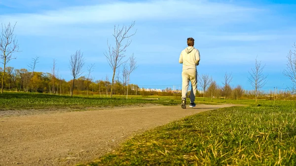 Man runs through the Park. A man in a track suit running down the path. Man jogging in park. High quality photo