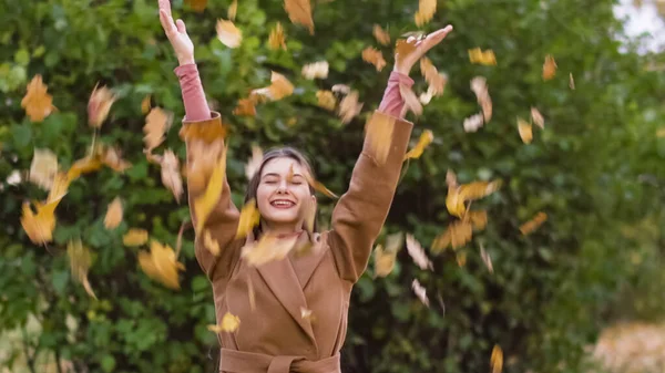 Happy Girl Throws Autumn Leaves. Falling autumn leaves in park. High quality photo