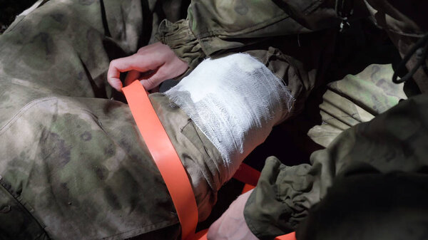 Врач переедает жгут с перевязанной ноги. Высокое качество фото