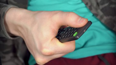 Adam TV kumandasının kırmızı düğmesine basıyor. Yüksek kalite fotoğraf