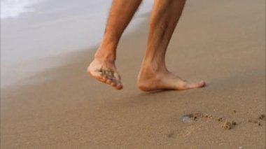 Kumsalda yürüyen bir adam kumsalda ayak izi bırakıyor. Yüksek kaliteli video