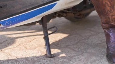 Kovboy çizmeli kadınlar motorsikletin karyolasını kaldırır. Yüksek kaliteli video