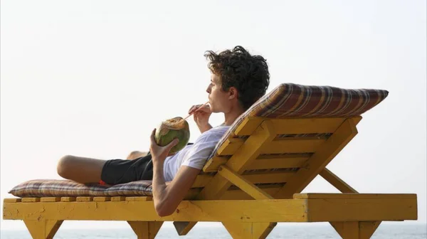 Man Drinking Coconut on a beach lounger. High quality photo