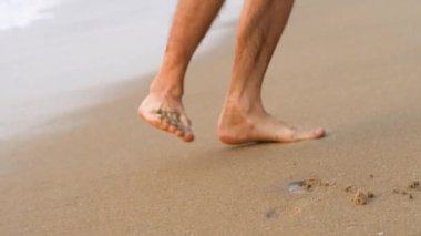 Mens ayakları deniz kıyısında ıslak kumda yürür. Yüksek kaliteli video