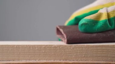 Erkek eli zımpara kağıdıyla ahşap yüzeyi zımparalıyor. Yüksek kaliteli video