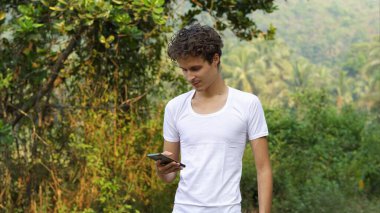 Yeşil orman arka planında cep telefonu kullanan kişi. Yüksek kalite fotoğraf