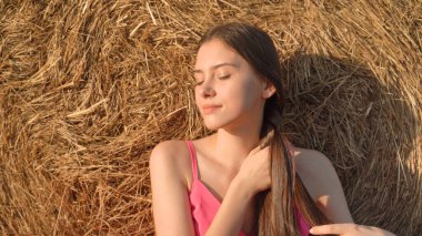 Kırsal genç kadın samanlığın yanında bir saç örgüsü örüyor. Yüksek kalite fotoğraf