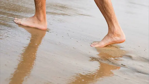 Men feet walk on wet sand by the water. High quality photo