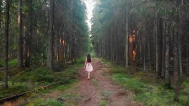 Pembe elbiseli kız ormanda bir patika boyunca yürüyor. Yüksek kaliteli video