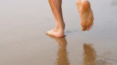 Erkek bacakları ıslak kumda koşar. Yüksek kaliteli video