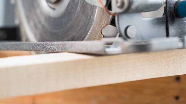 Carpenter cutting wood. Electric circular saw close up. High quality photo