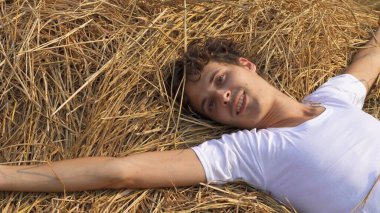 Genç adam samanlıkta altın bir balyanın üzerinde yatmaktan hoşlanıyor. Yüksek kalite fotoğraf