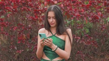 Yong Woman cep telefonunun ekranına bakıyor. Yeşil güzel elbise. Yüksek kalite 4k görüntü
