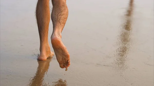 Mens feet walk on wet sand by the sea. High quality photo