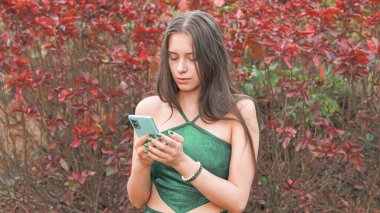 Yong Woman cep telefonunun ekranına bakıyor. Yeşil güzel elbise. Yüksek kalite fotoğraf