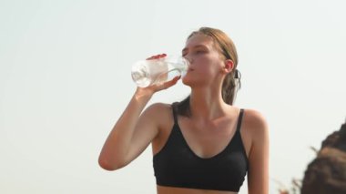 Spor eğitiminde su şişesinden su içen atletik bir kız. Yüksek kalite 4k görüntü