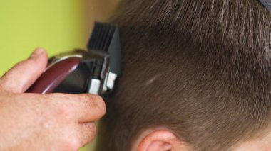 Genç bir adam bir berber dükkanında elektrikli makasla saçını kestiriyor. Yüksek kalite fotoğraf