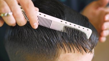 Kuaför beyaz taraklı genç bir adamın saçlarını tarıyor. Yüksek kalite fotoğraf