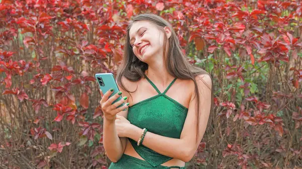 young woman holding a phone against a background of tropical flowers. High quality photo