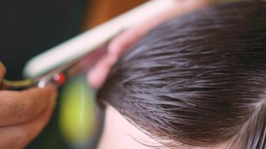 Genç bir adama kâkül yapmak için altın makas ve tarak kullanan bir kuaför. Yüksek kalite 4k görüntü