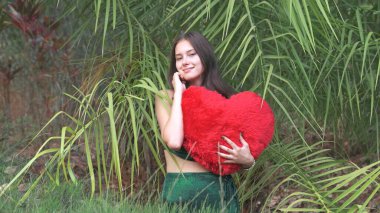Sevgililer Günü 'nde parkta büyük kırmızı bir kalp taşıyan romantik esmer bir kadın. Yüksek kalite fotoğraf