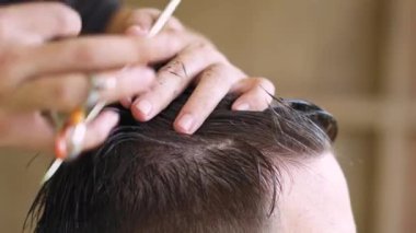 Makas ve tarak kullanan genç bir adam için modaya uygun saç stili yapan kuaför. Yüksek kalite 4k görüntü