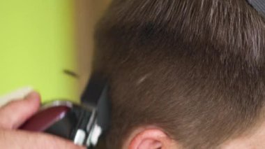 Genç bir adam bir berber dükkanında elektrikli makasla saçını kestiriyor. Yüksek kalite 4k görüntü
