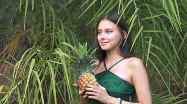 Egzotik bir ormanın önünde ananas tutan genç bir kadın. Yüksek kalite fotoğraf